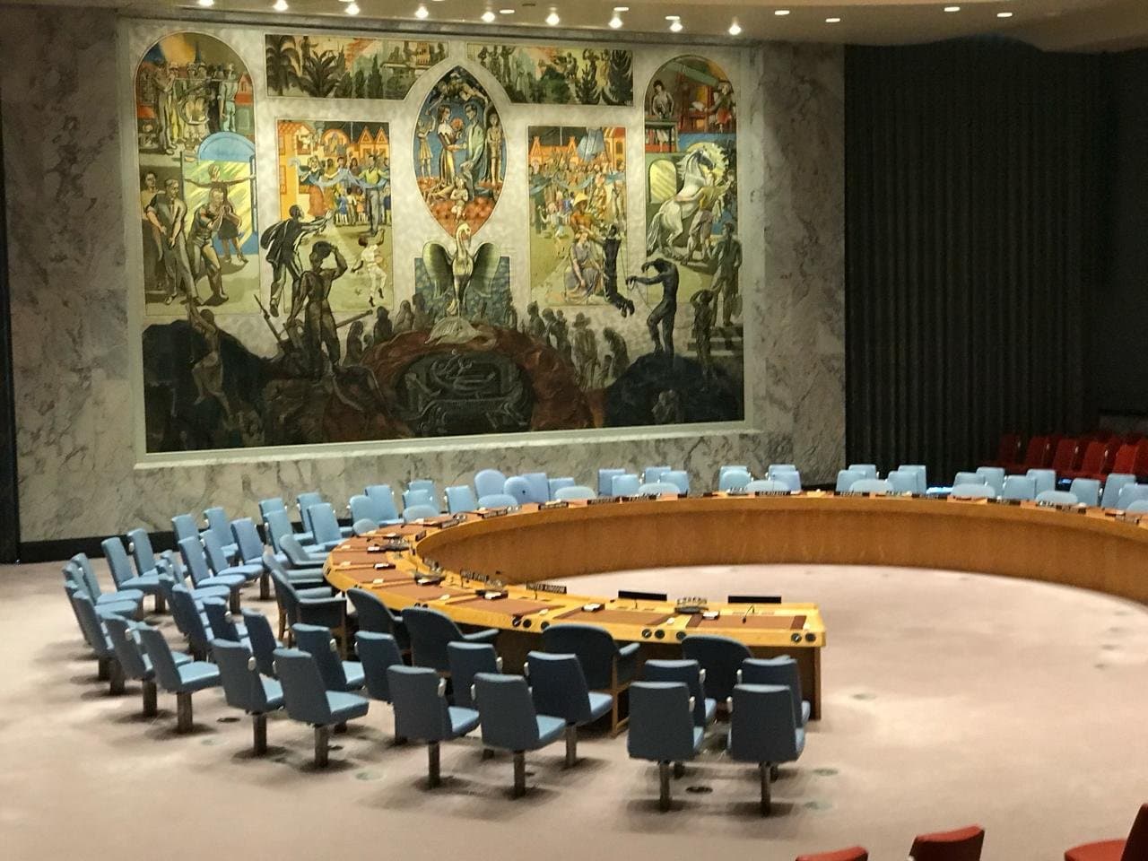 Sala del Consejo de Seguridad de las Naciones Unidas, con su mesa en herradura y el mural al fondo